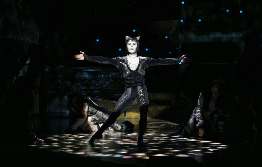 Mr Mistoffelees dancing with arms outstretched on the Cats the Musical stage