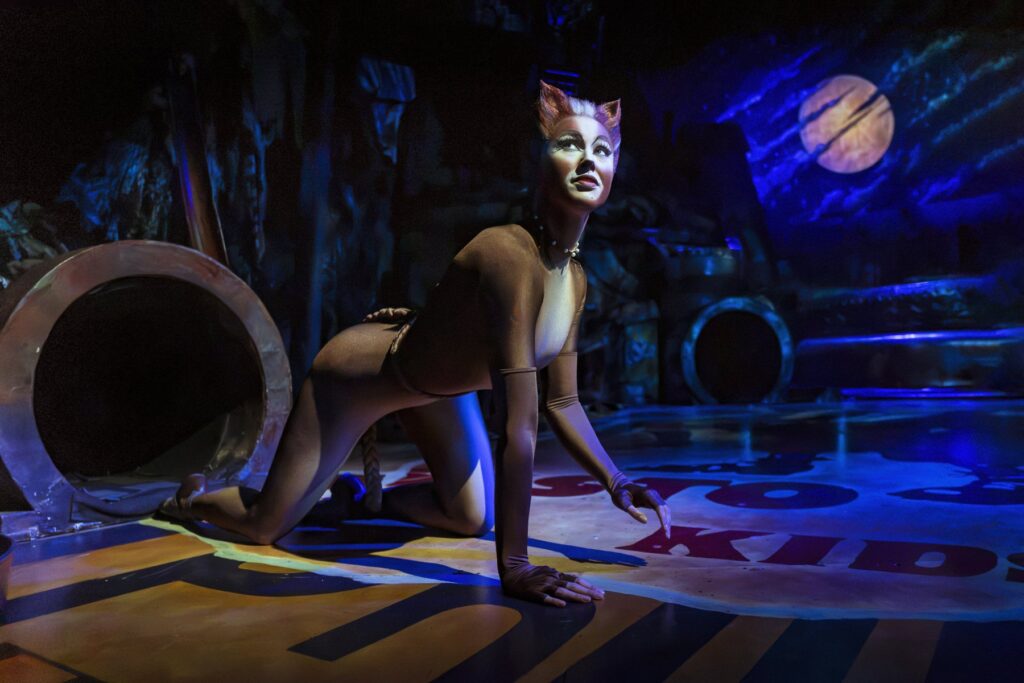 Cassandra crawling across the junkyard stage in Cats the Musical
