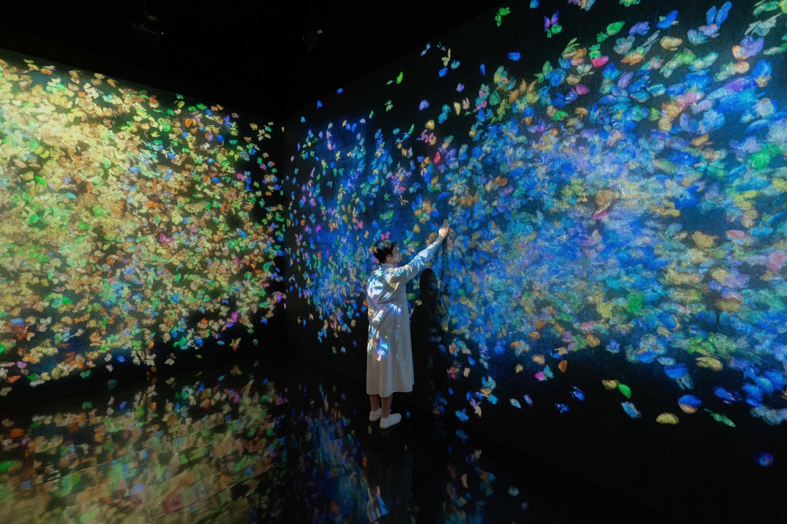 A visitor surrounded by projected butterflies at teamLab, one of our November date ideas in Singapore