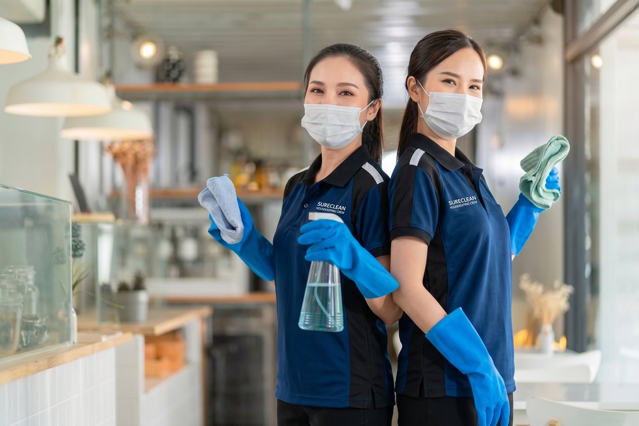Two Sureclean cleaners holding cleaning supplies in a Singapore home